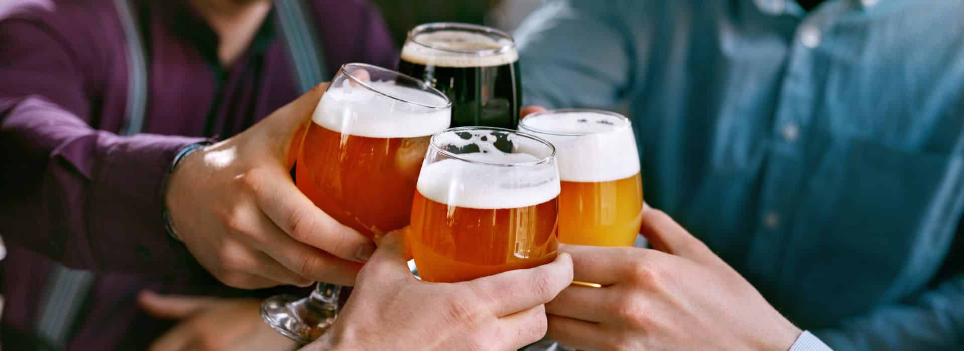 Four hands raising and clinking beer glasses
