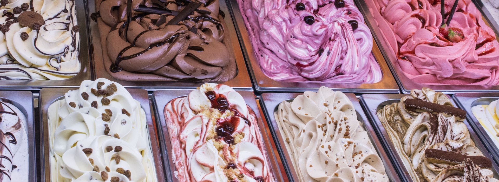 Two rows of ice cream tubs filled with different flavors of ice cream