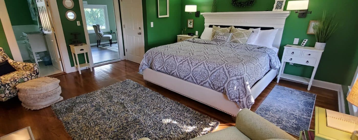 Dark green walls, hardwood floors white headboard