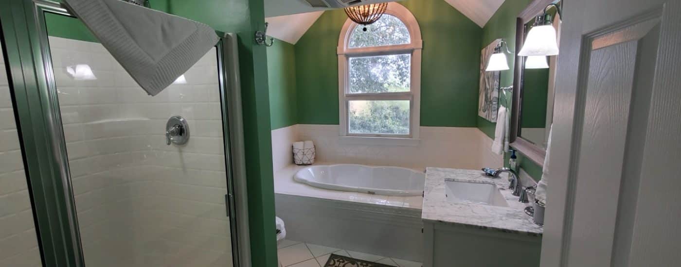 Green bathroom with white counter top and soaking tub