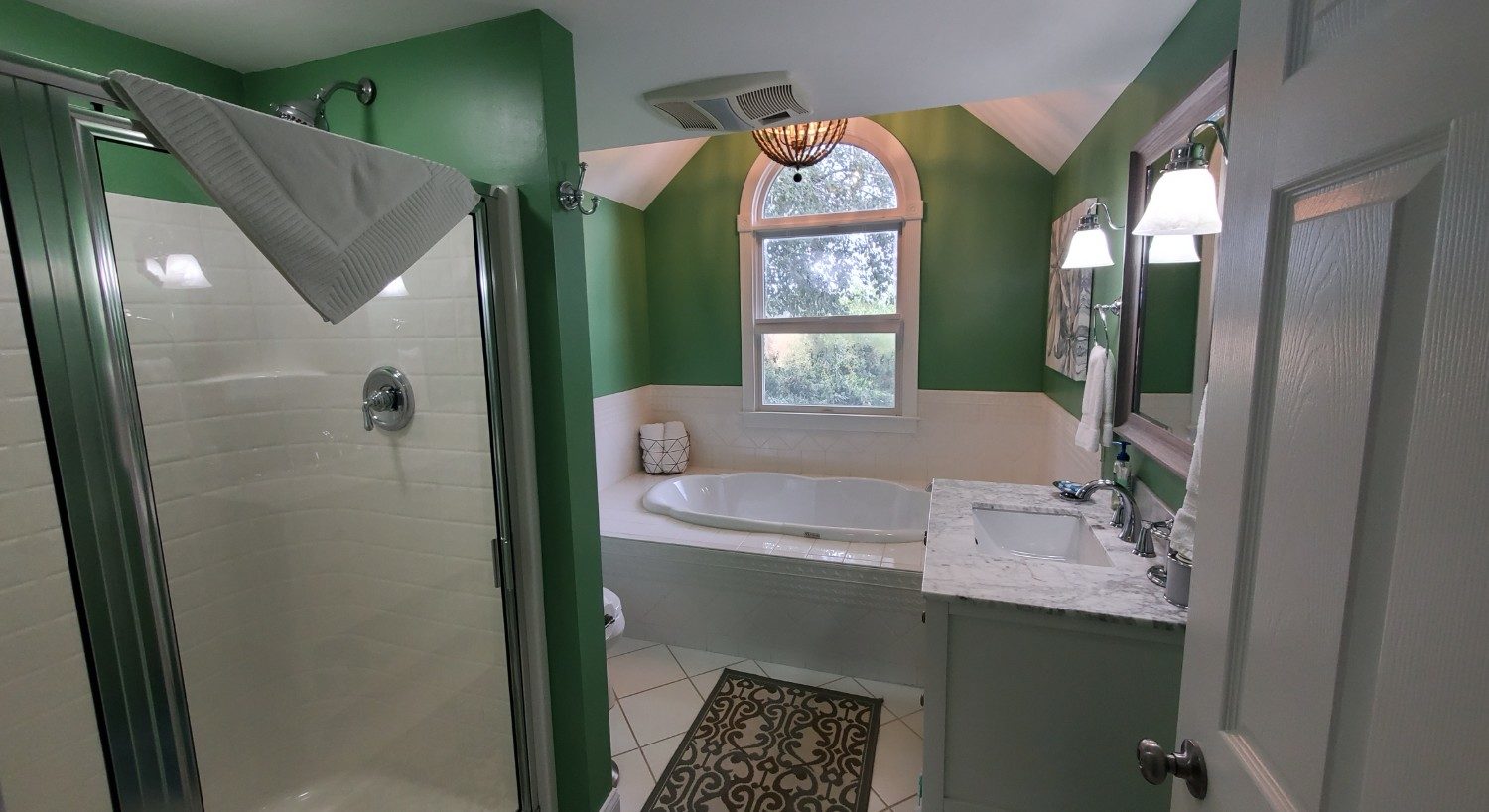 Green bathroom with white counter top and soaking tub