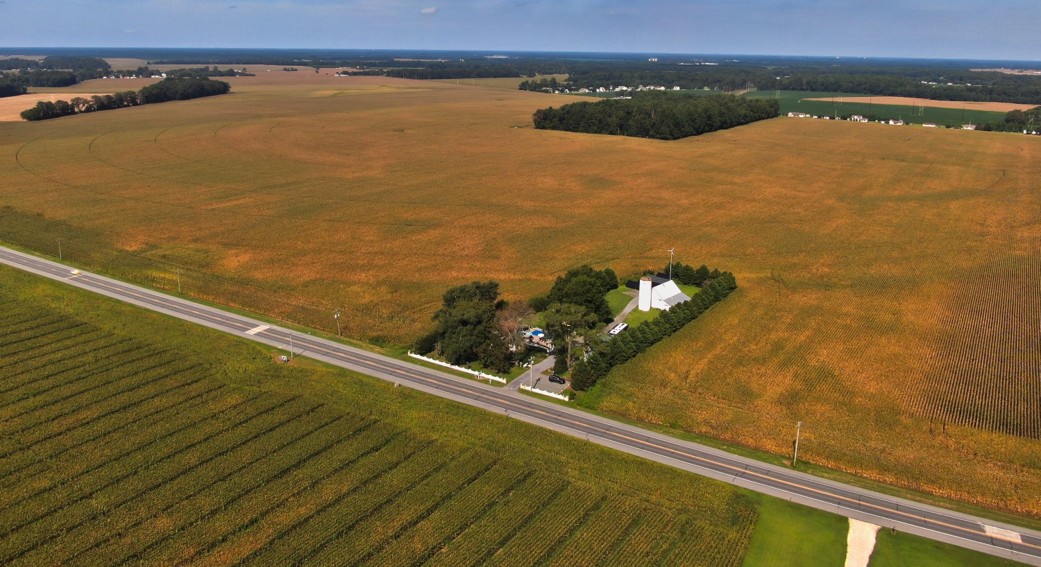 Drone shot of property with green grass and old white farm house