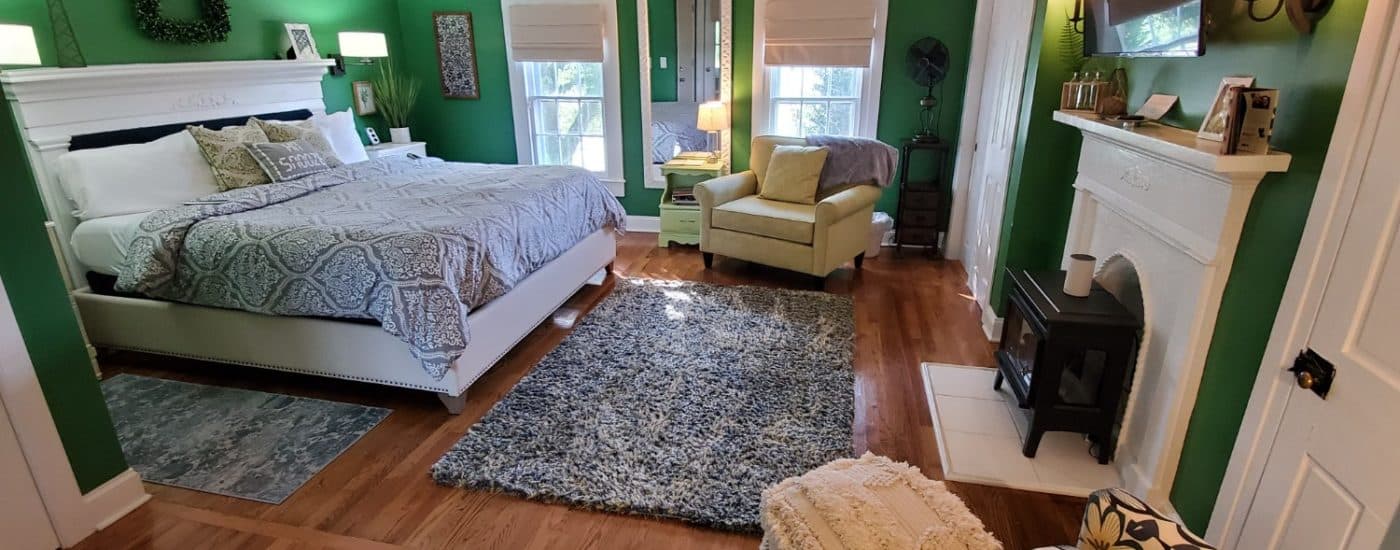 Dark green walls, hardwood floors white headboard