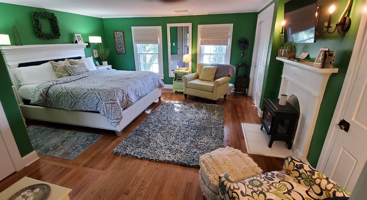 Dark green walls, hardwood floors white headboard