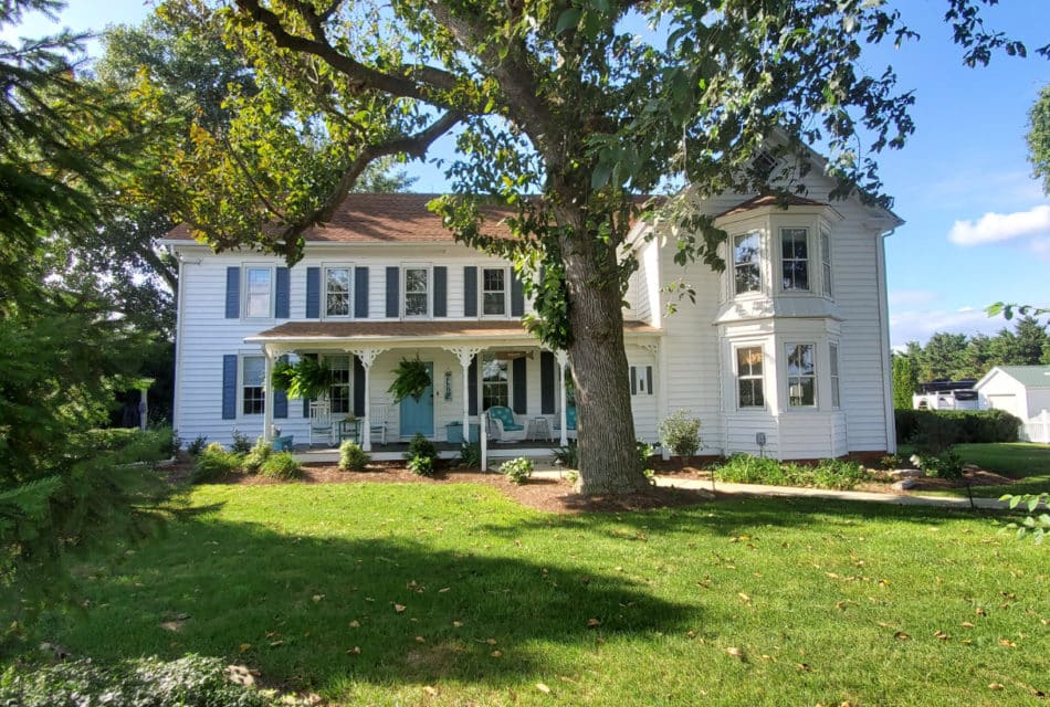 white farm house will green trees