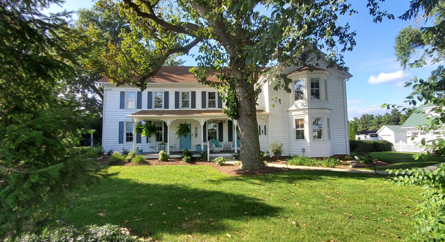 white farm house will green trees