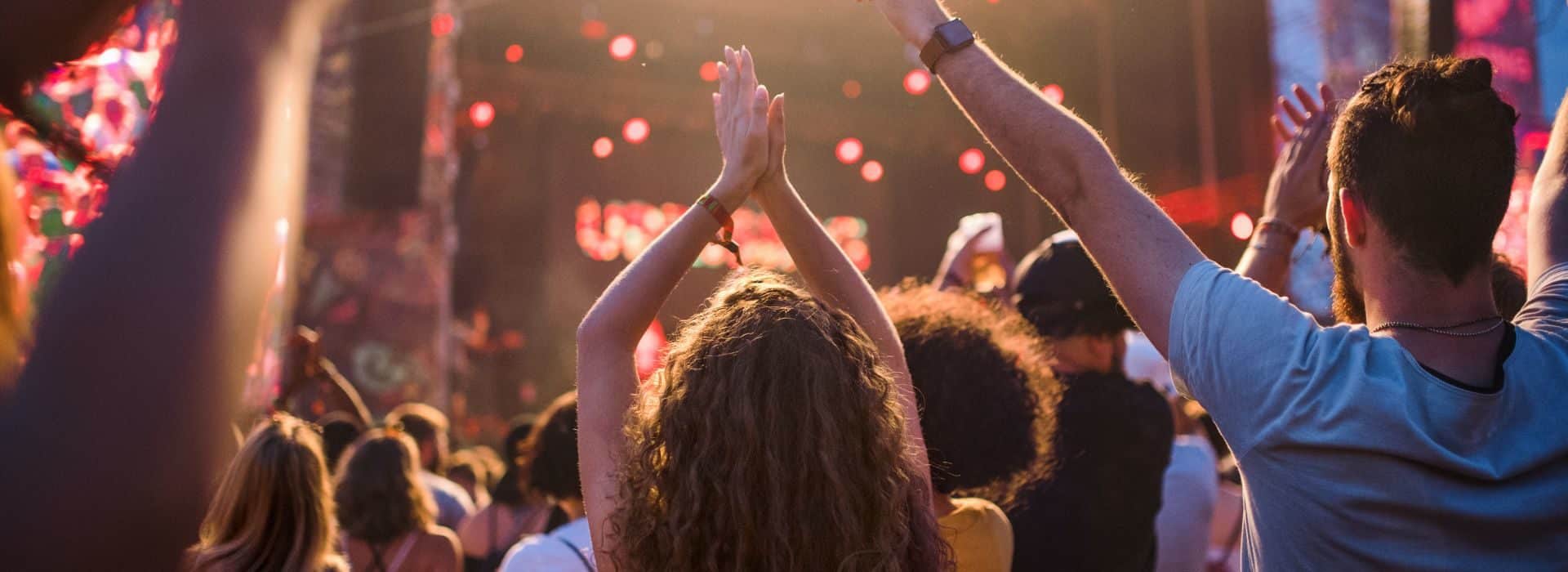 A crowd of people with arms raised toward a live concert stage.