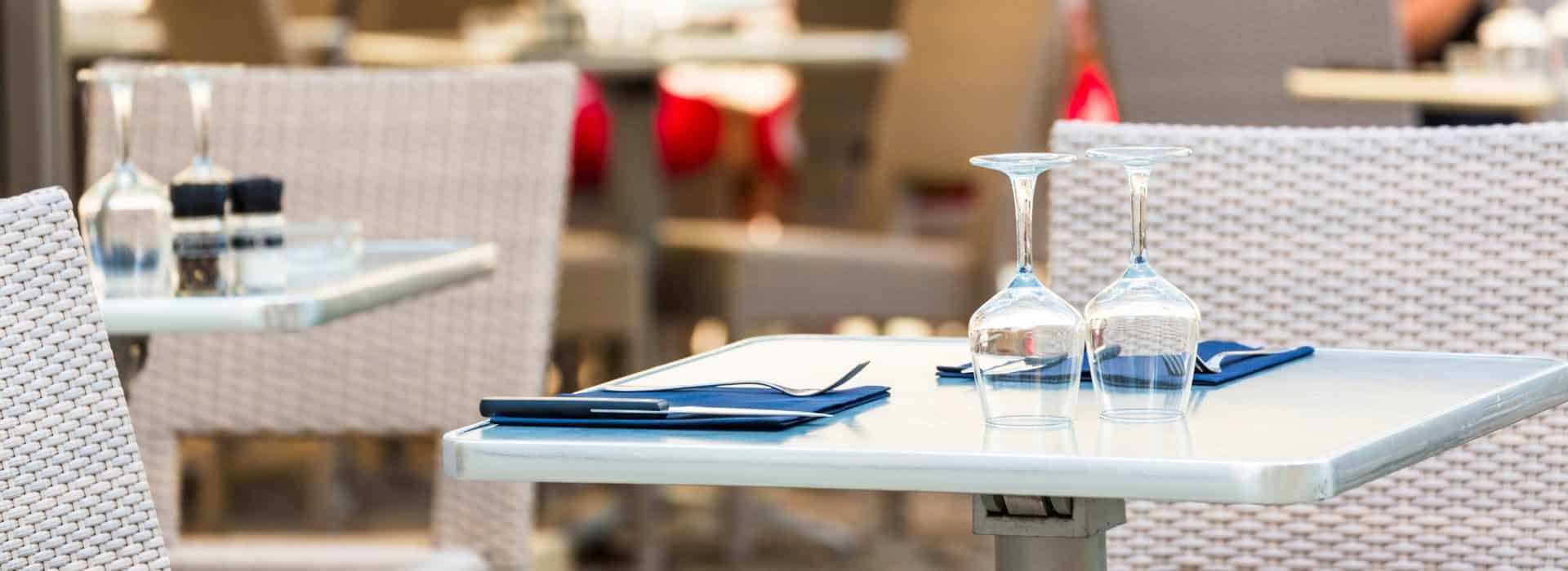 Outdoor dining tables set with blue linen napkins and wine glasses