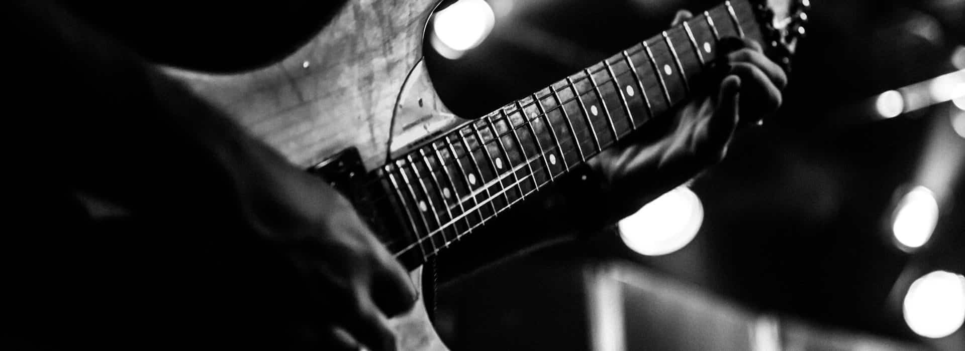 Black and white photo of man's hands playing a guitar