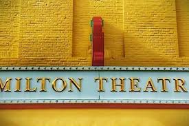 Milton theatre sign yellow and red on brick building